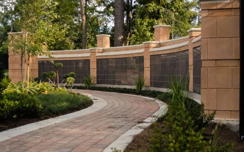Curved paved walkway beside planting and a boundary wall